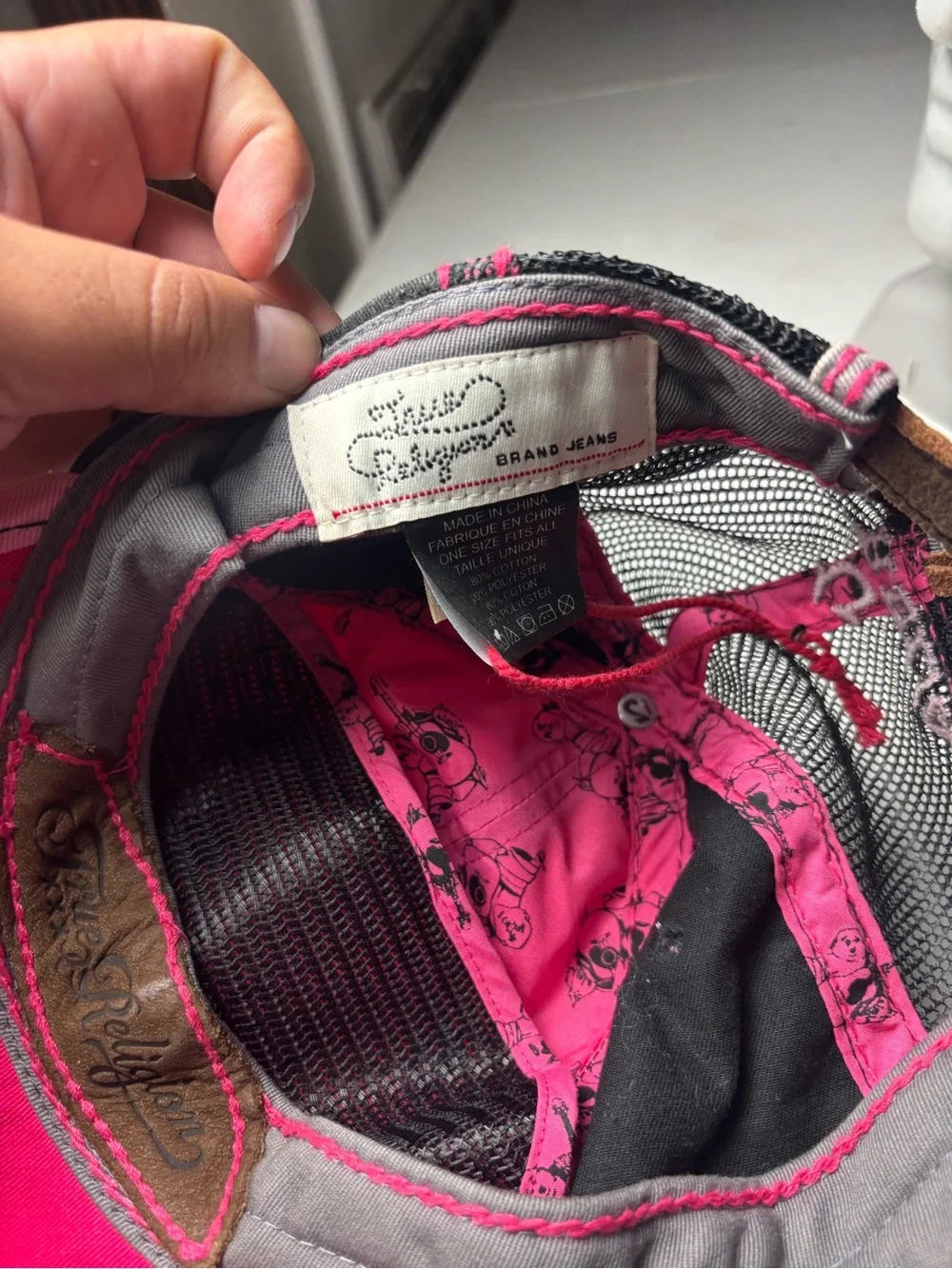 pink, distressed True Religion brand jeans cap with embroidered wings and a logo